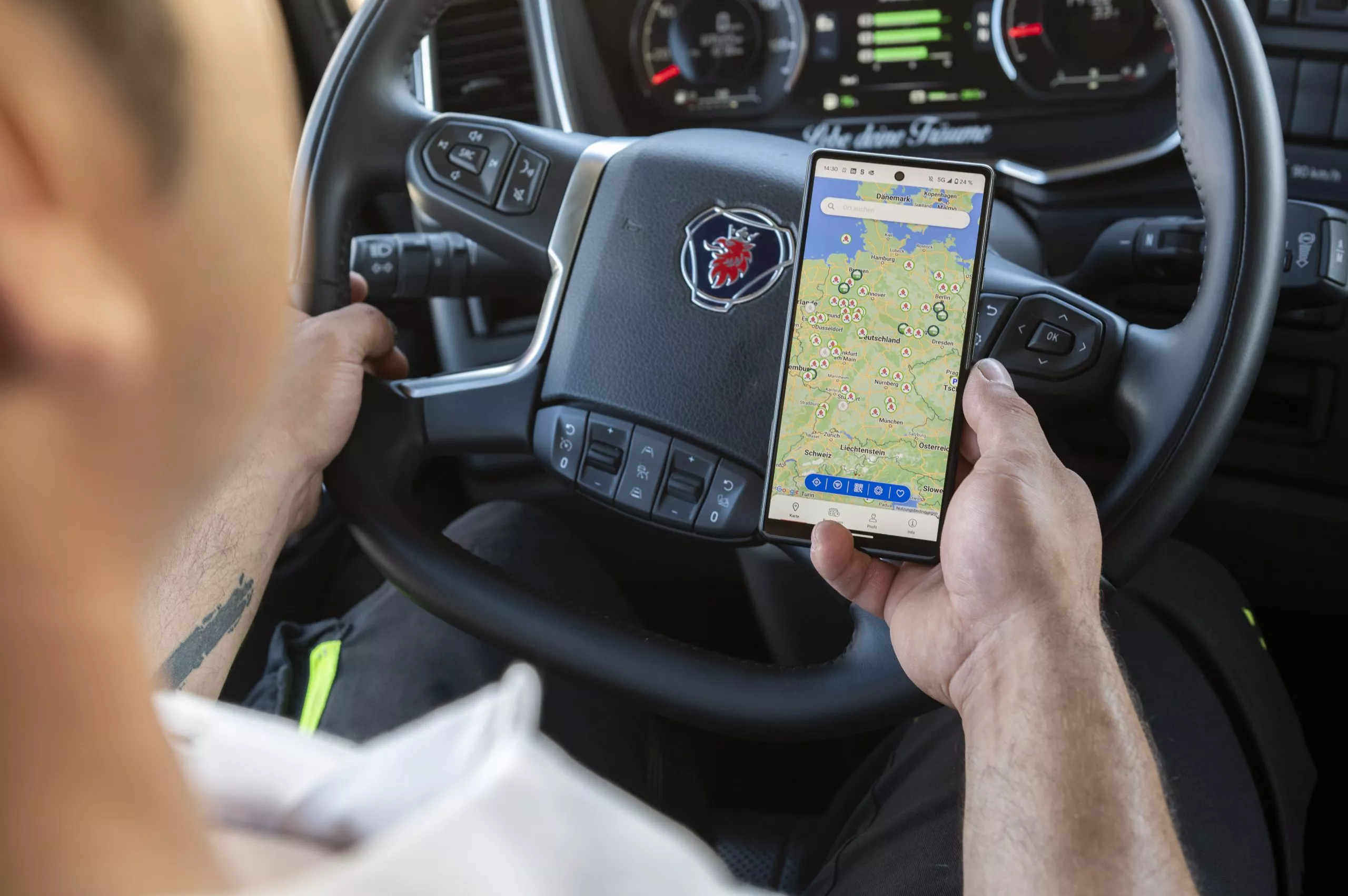 LKW Fahrer hält Smartphone mit Landkarte in der Hand